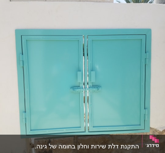 חלון מתכת תכלת עם מסגרת על קיר לבן